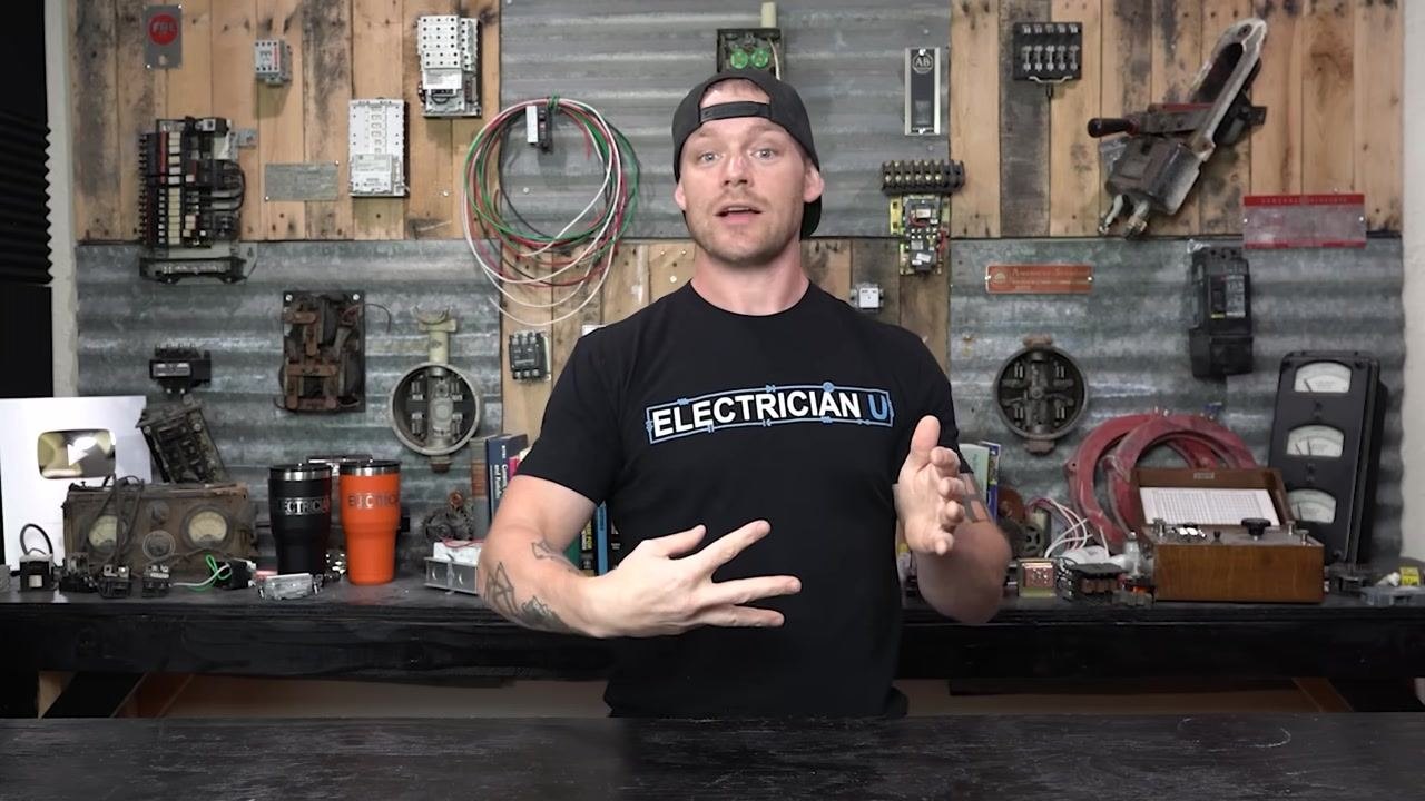 Presenter describing shunt trip breakers and secondary circuits, gesturing energetically in the workshop