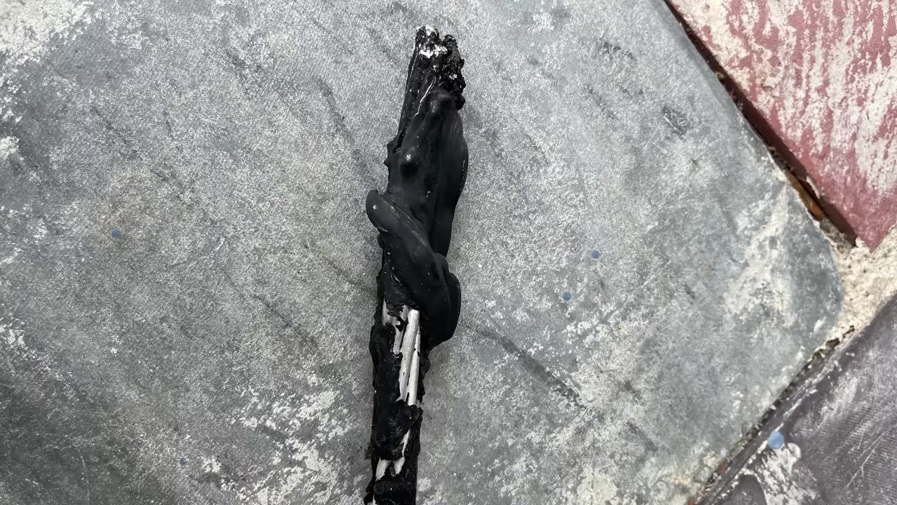 Close-up of severely melted and charred electrical wire, showing extreme overheating and insulation failure