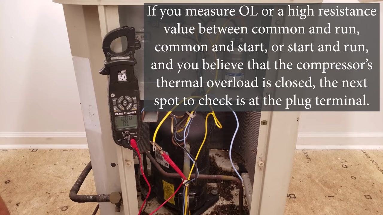 Compressor plug area with the technician's hand preparing to remove the plug