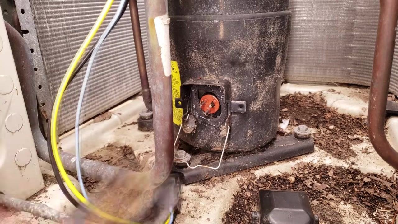 Compressor plug area with exposed terminals as the technician holds the plug connector