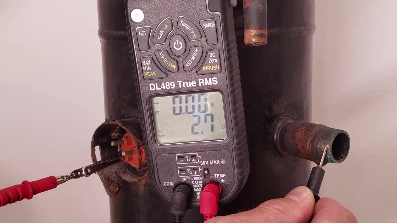 Multimeter display showing 2.7 MΩ on the repeated test, with probes still on the terminal and copper tube