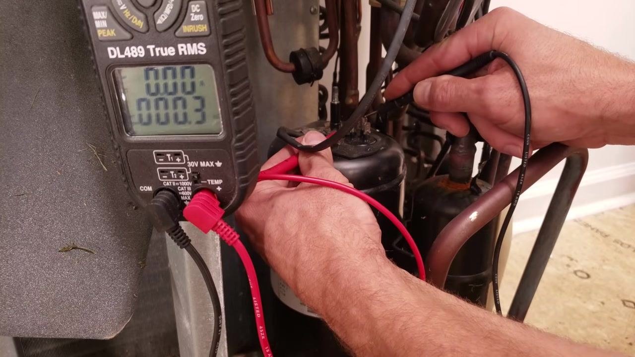 Technician measuring resistance between compressor terminal pairs, with the multimeter display showing 0.3 ohms