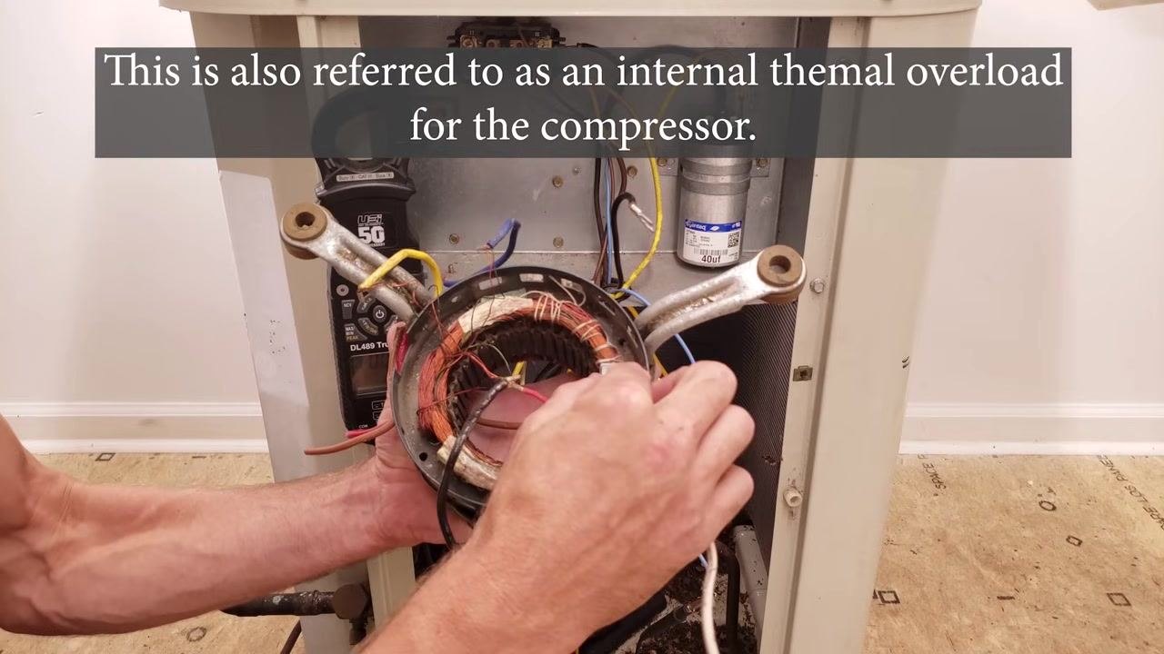 Technician holding a motor stator with visible windings, demonstrating the location and function of the internal thermal overload protector