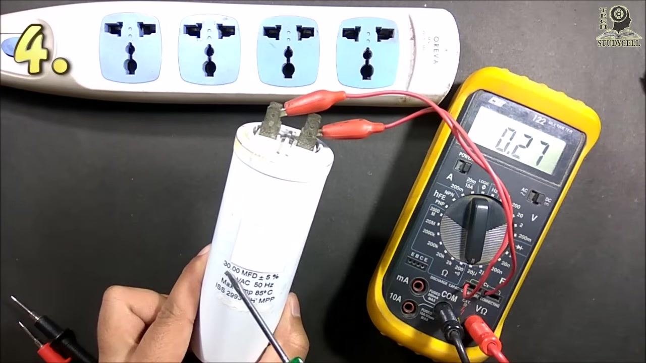 The multimeter display showing "9.30" while the alligator clips remain attached to the capacitor