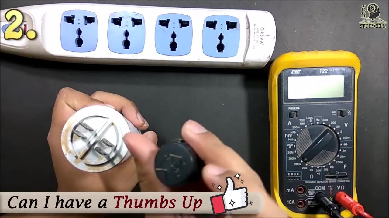 The user holding the capacitor and buzzer, preparing to connect the buzzer across the capacitor terminals