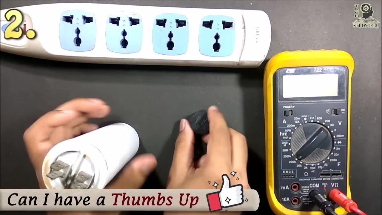 The capacitor being charged with a DC source using black and red probes, with the buzzer placed on the table ready for use as a load