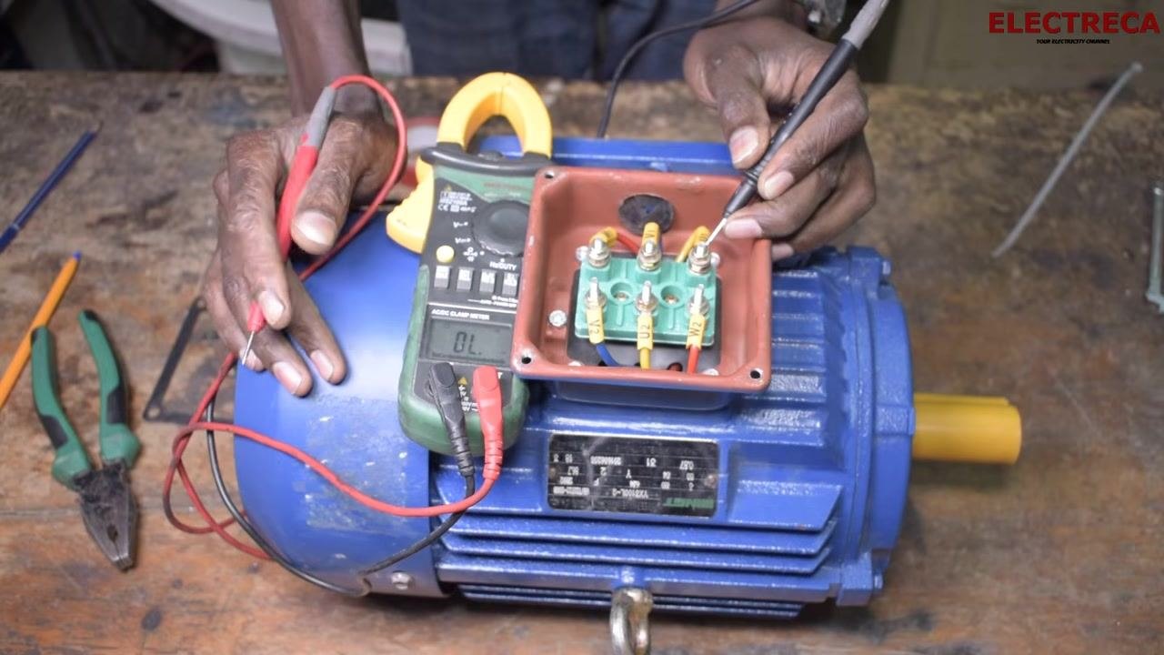 Multimeter probe touching the motor body and another touching a terminal, with the display showing "OL" (open loop) and the labeled terminal block (U1, U2, V1, V2, W1, W2) visible.