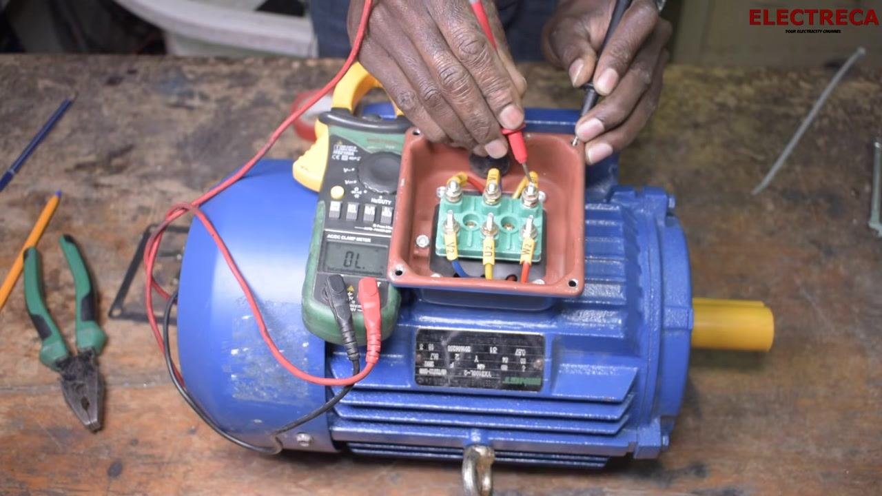 Multimeter probes positioned between the motor body and terminal U1, with the display showing "OL" (open loop), confirming no ground leakage.
