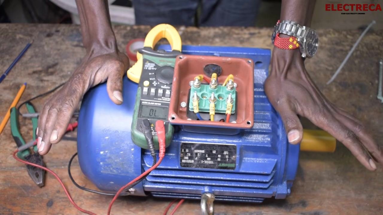 Both hands placed on the motor, with the multimeter and terminal block visible, indicating testing is complete and the motor is ready for use.