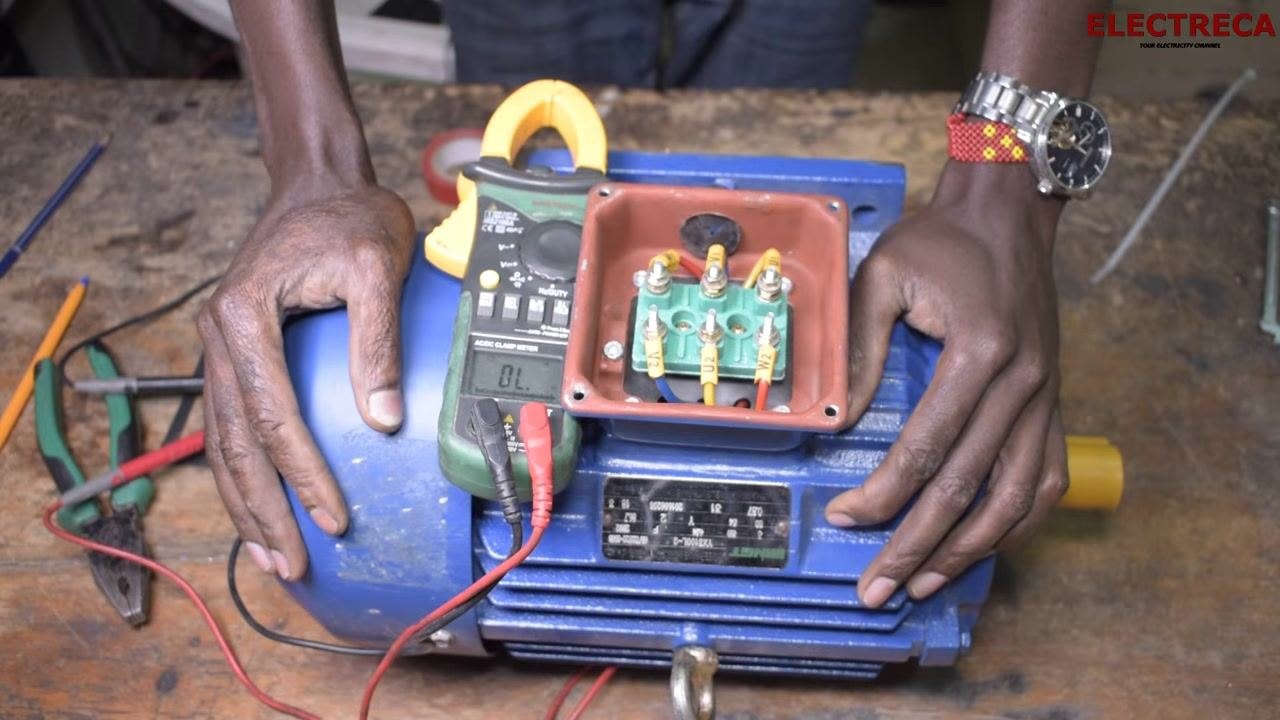 Hands holding the motor, reinforcing the importance of completing all tests before powering the motor, with the multimeter and terminal block still visible.