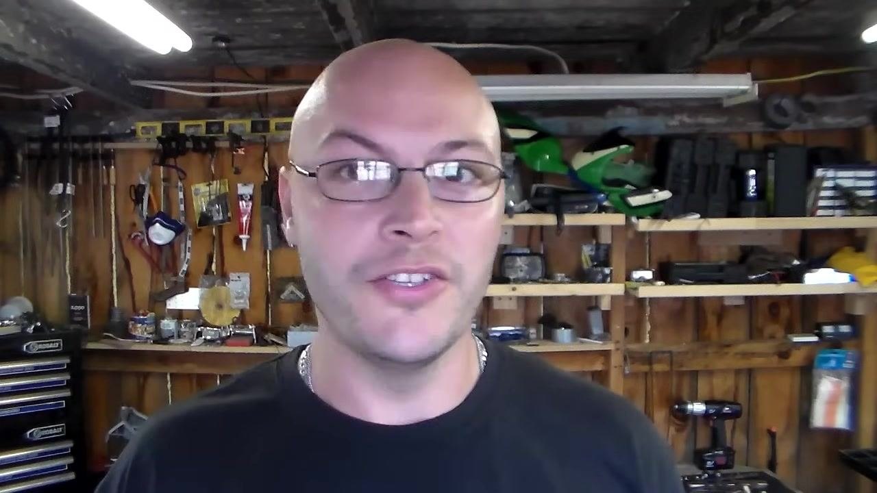 Presenter explaining universal replacement parts, with workshop tools and equipment in the background.