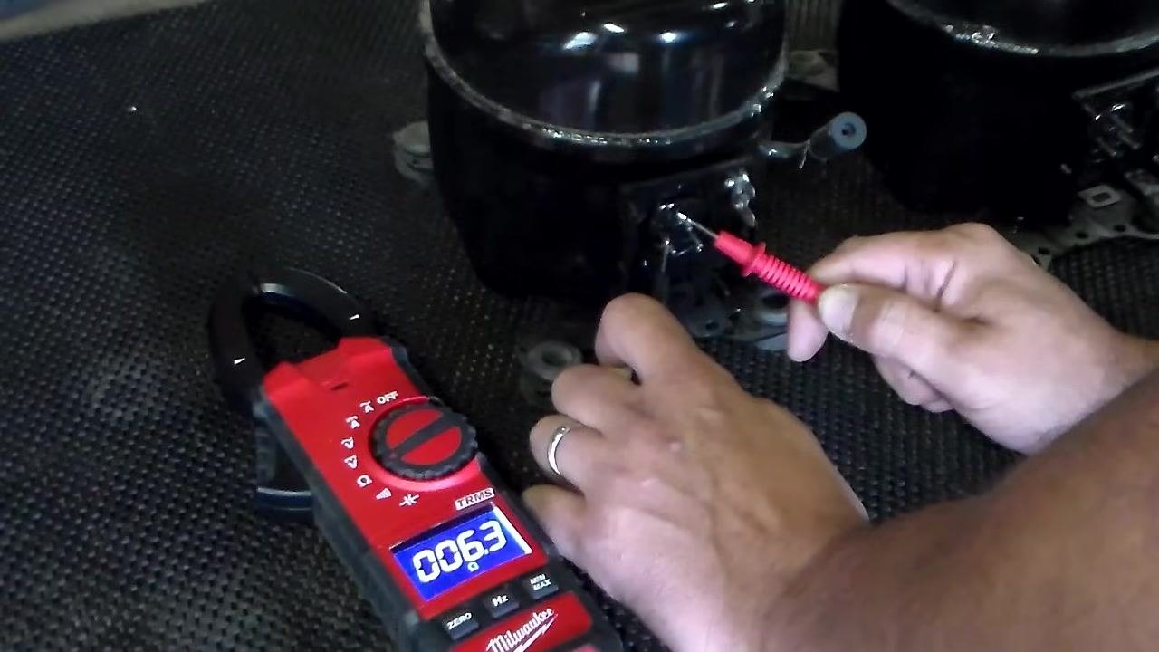 Probe held away from the compressor; multimeter displays "OL" (open loop)