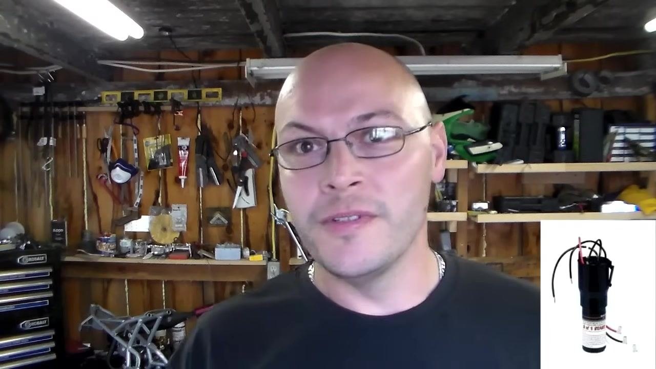 Person explaining the benefit of carrying spare start capacitors for compressor testing, workshop background.
