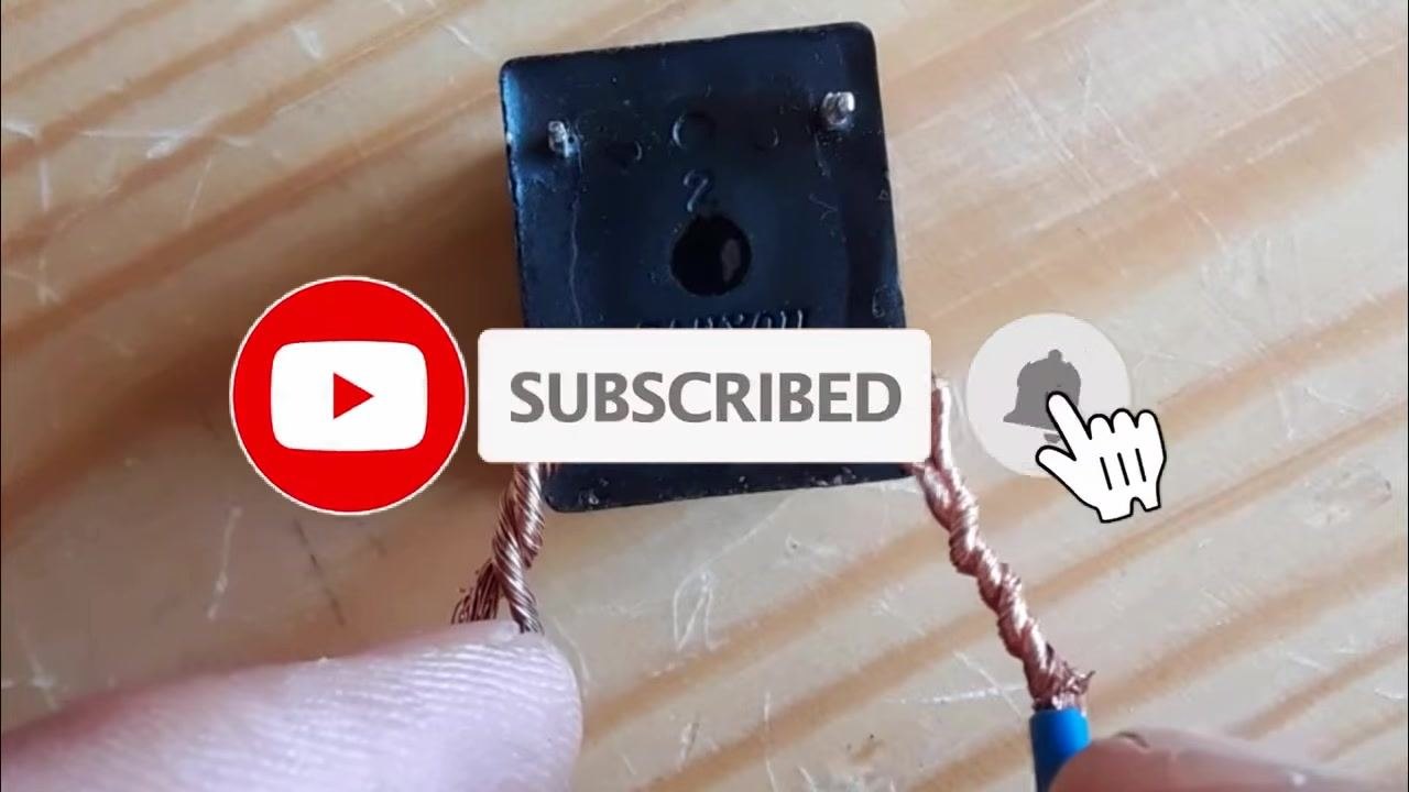 A relay on a wooden surface with two bare wires connected to its coil terminals, no voltage applied, multimeter not yet connected