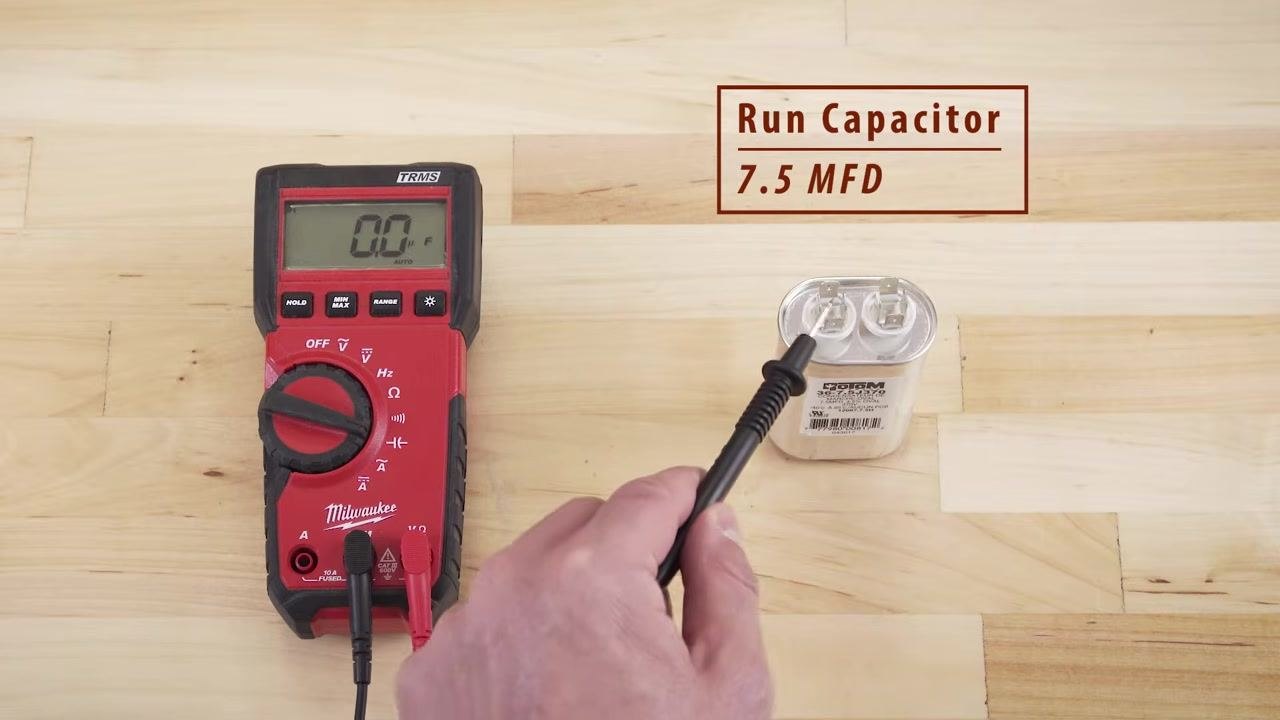 Multimeter showing 0.0 μF while testing a run capacitor labeled 7.5 MFD