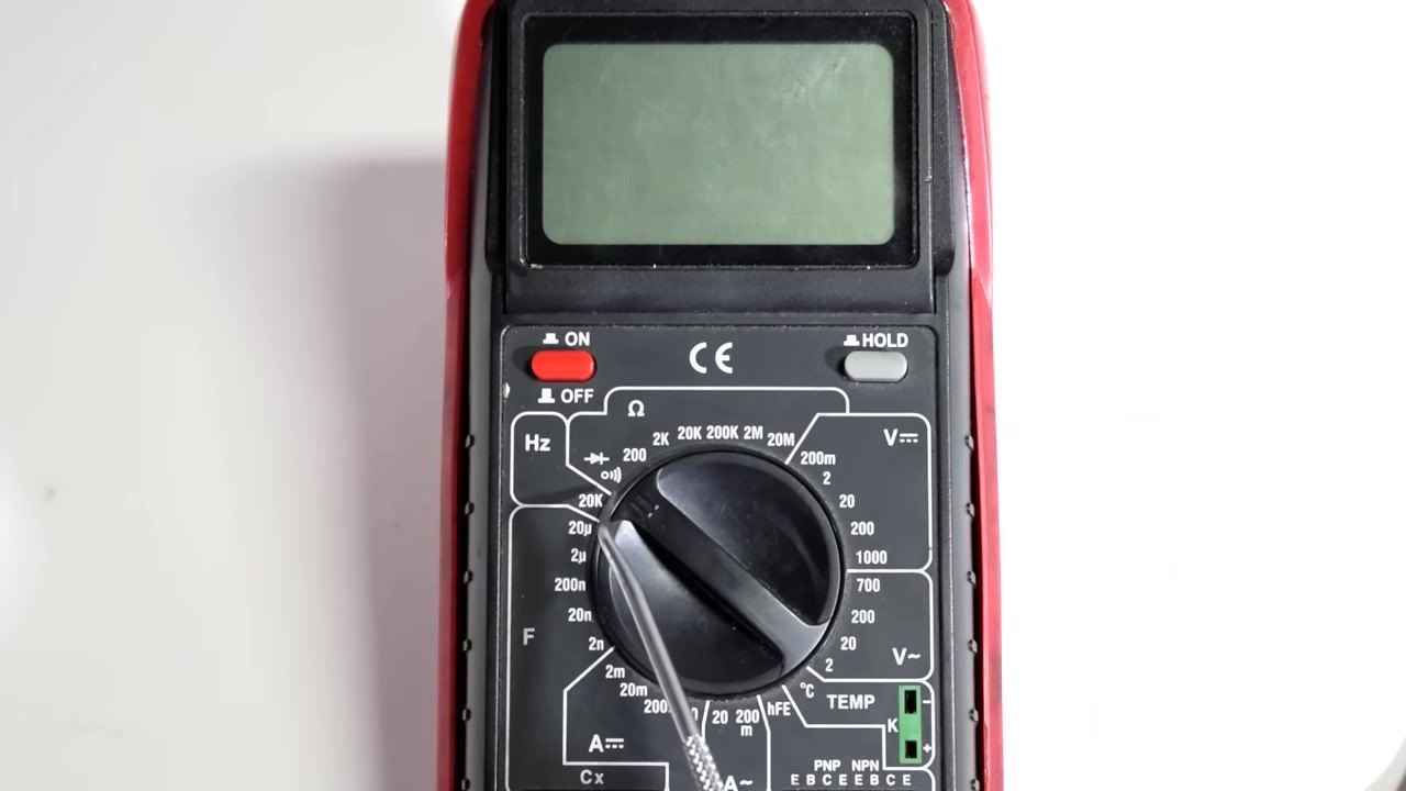Hands attaching test leads to wire ends and connector pins, with the multimeter display showing a measurement.
