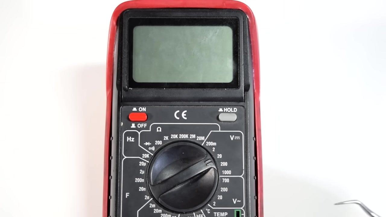 A hand points to the multimeter dial, highlighting the available measurement options.