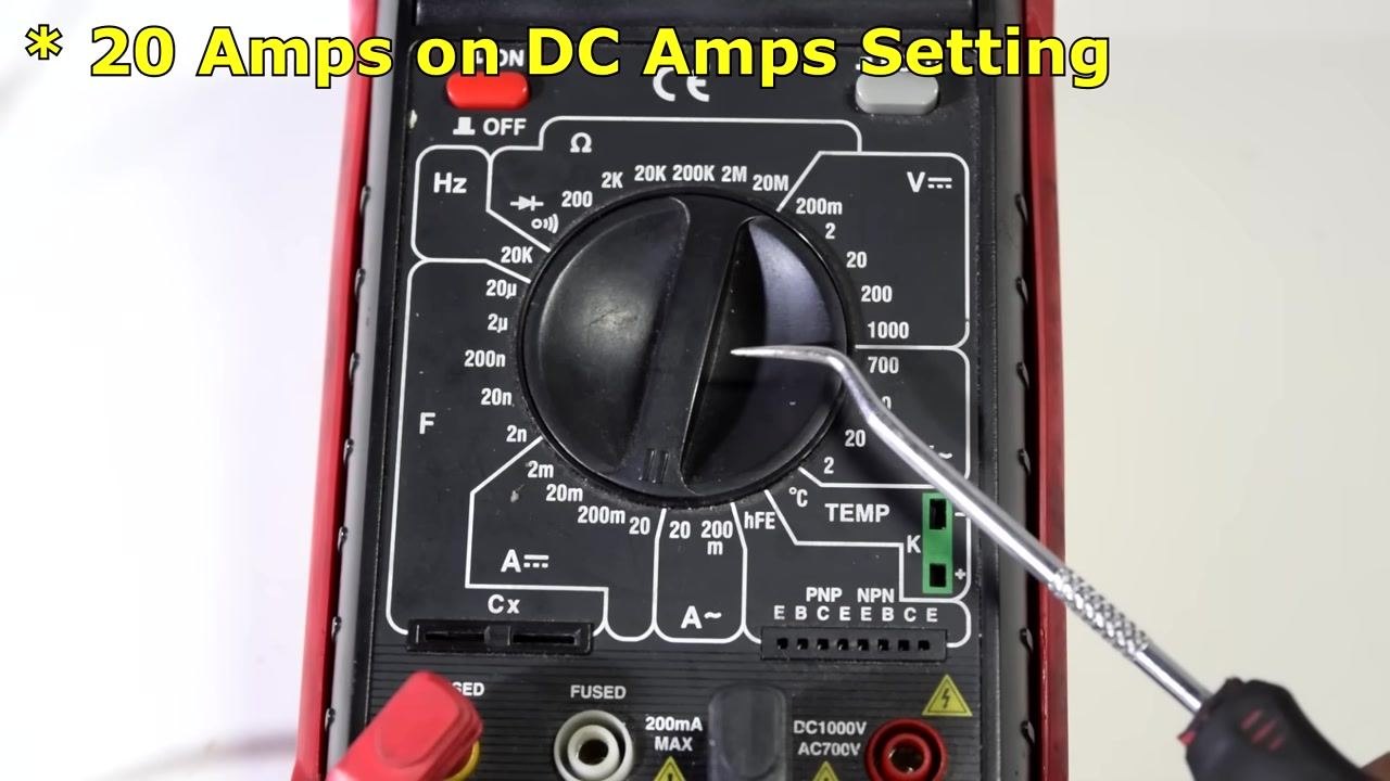 Multimeter dial set to 20A DC Amps, with a screwdriver pointing at the setting and clear label and port markings visible.