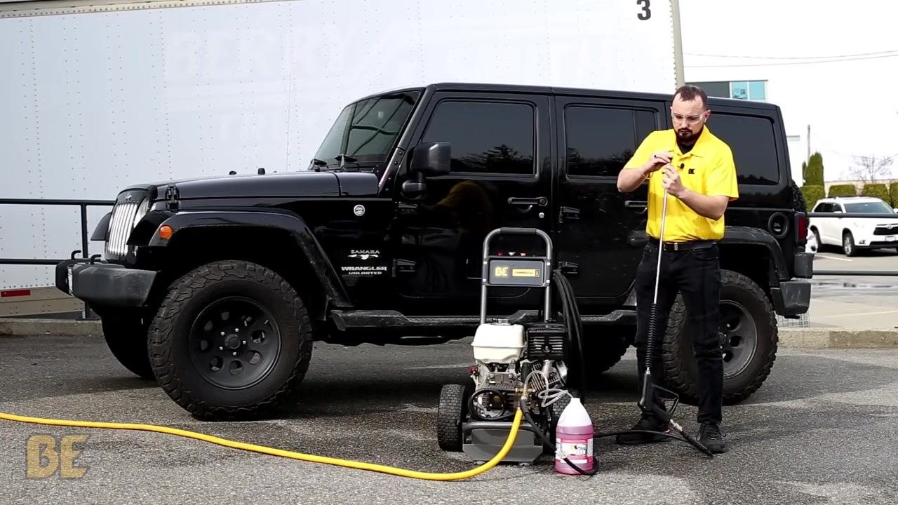 Person standing next to a BE Power Washer, attaching the black soaper tip to the end of the spray wand