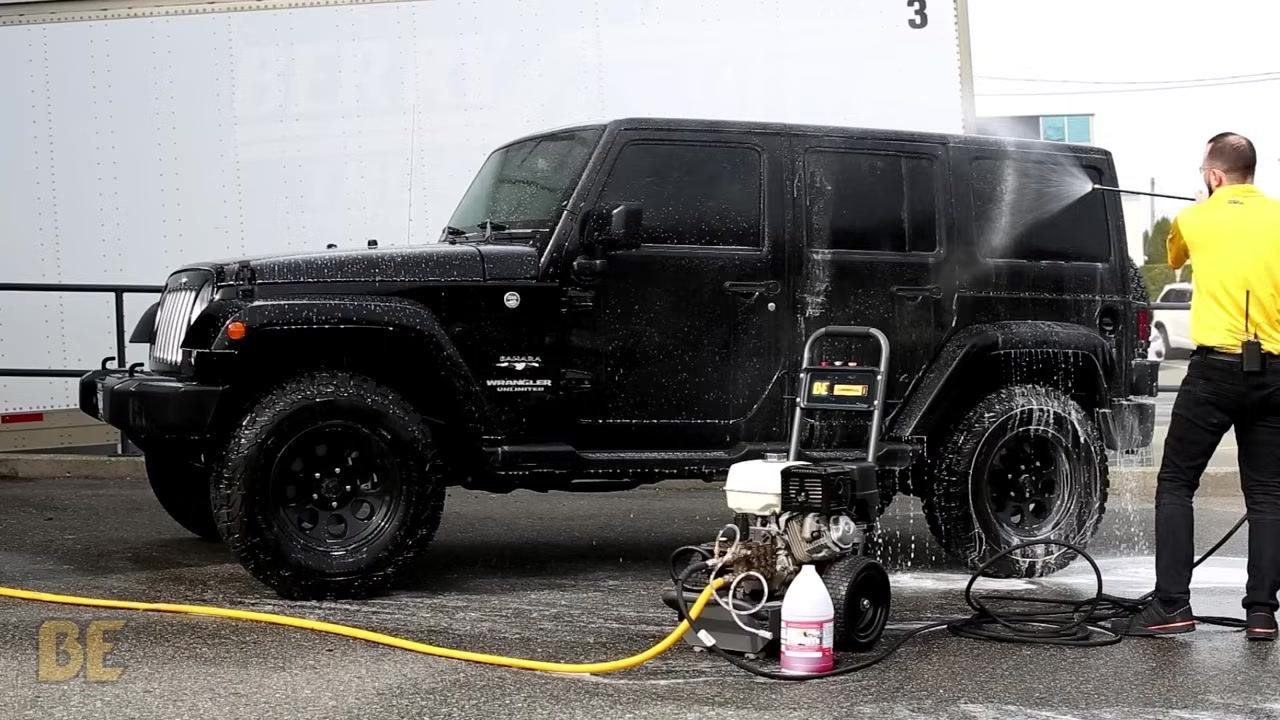 Person continues rinsing the Jeep, with mostly water coming out of the wand.