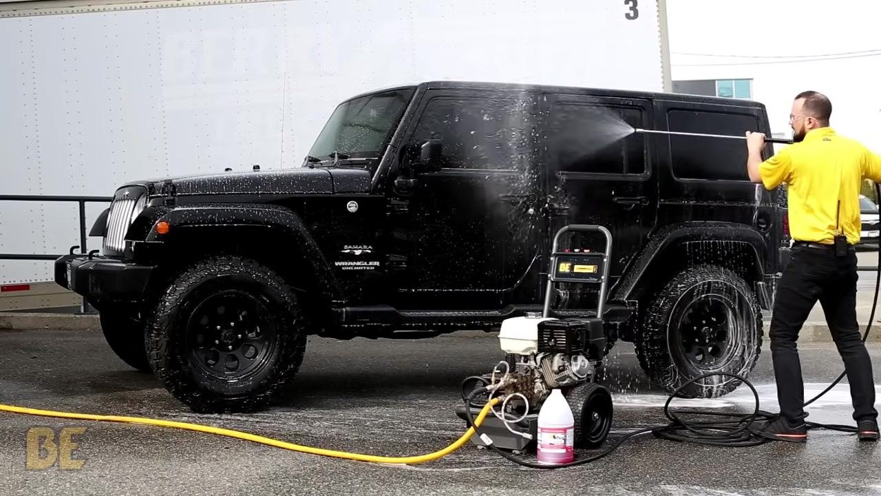 Person continues rinsing the Jeep, with mostly water coming out of the wand.