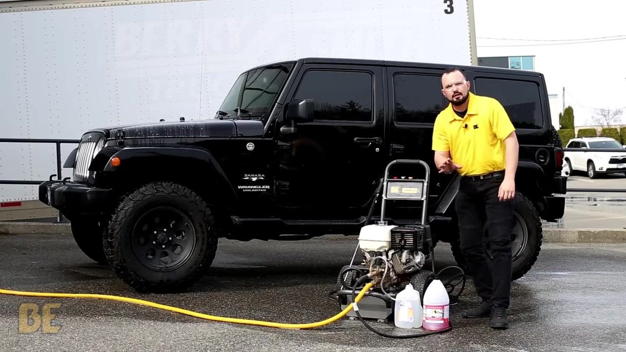 Person in a yellow shirt standing next to the BE Power Washer, with the soap injector hose placed in a clean bucket of water