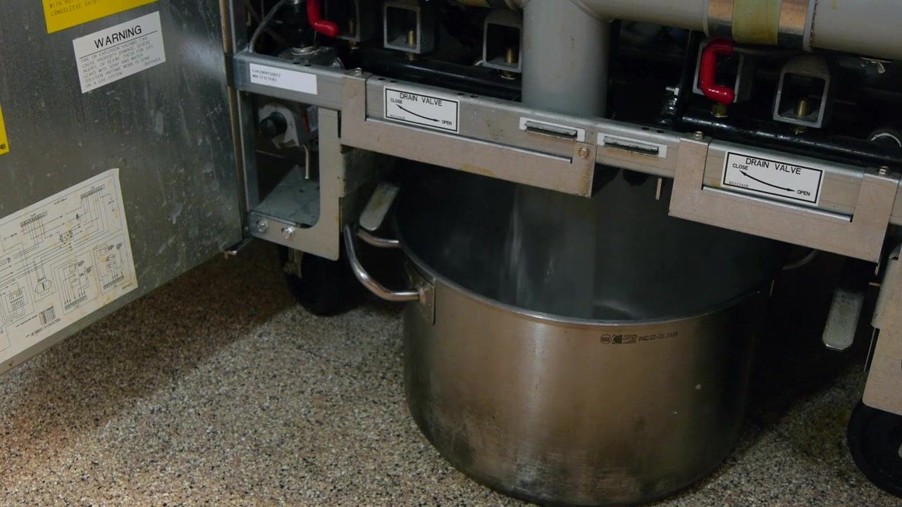 Close-up of a boil out puck held above the fryer basin, with water inside.