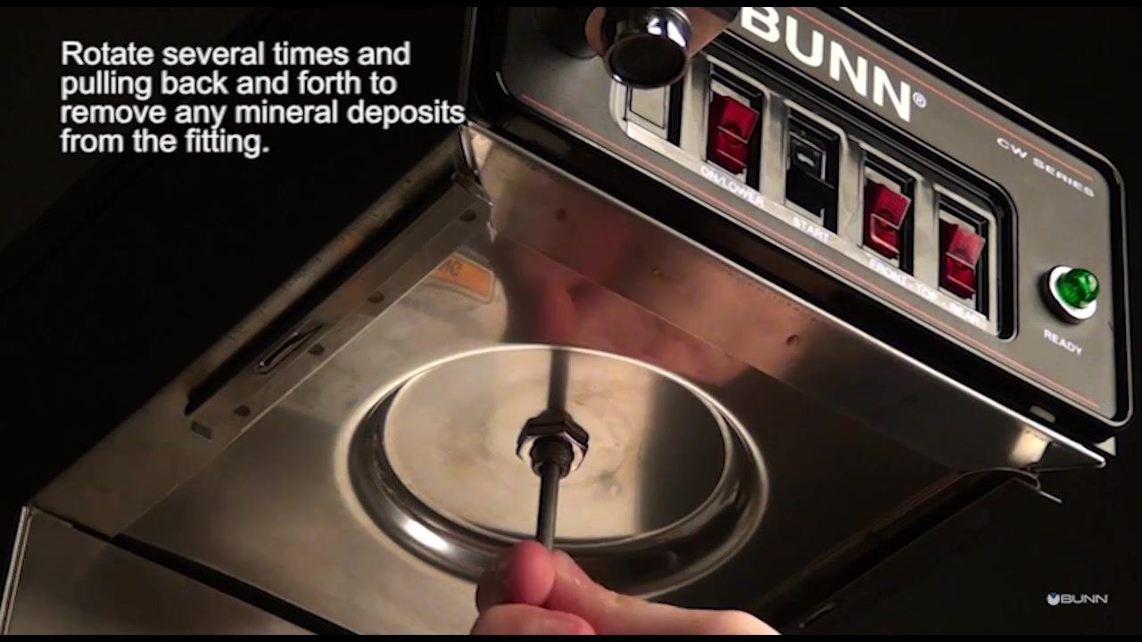A hand rotates and moves the deliming spring tool back and forth in the spray head fitting.