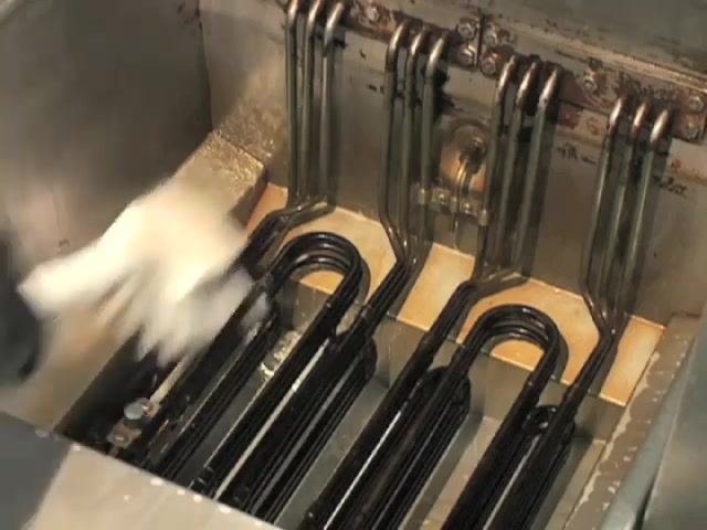 A gloved hand scrubs the top half of the fryer vat with a green scrub pad.