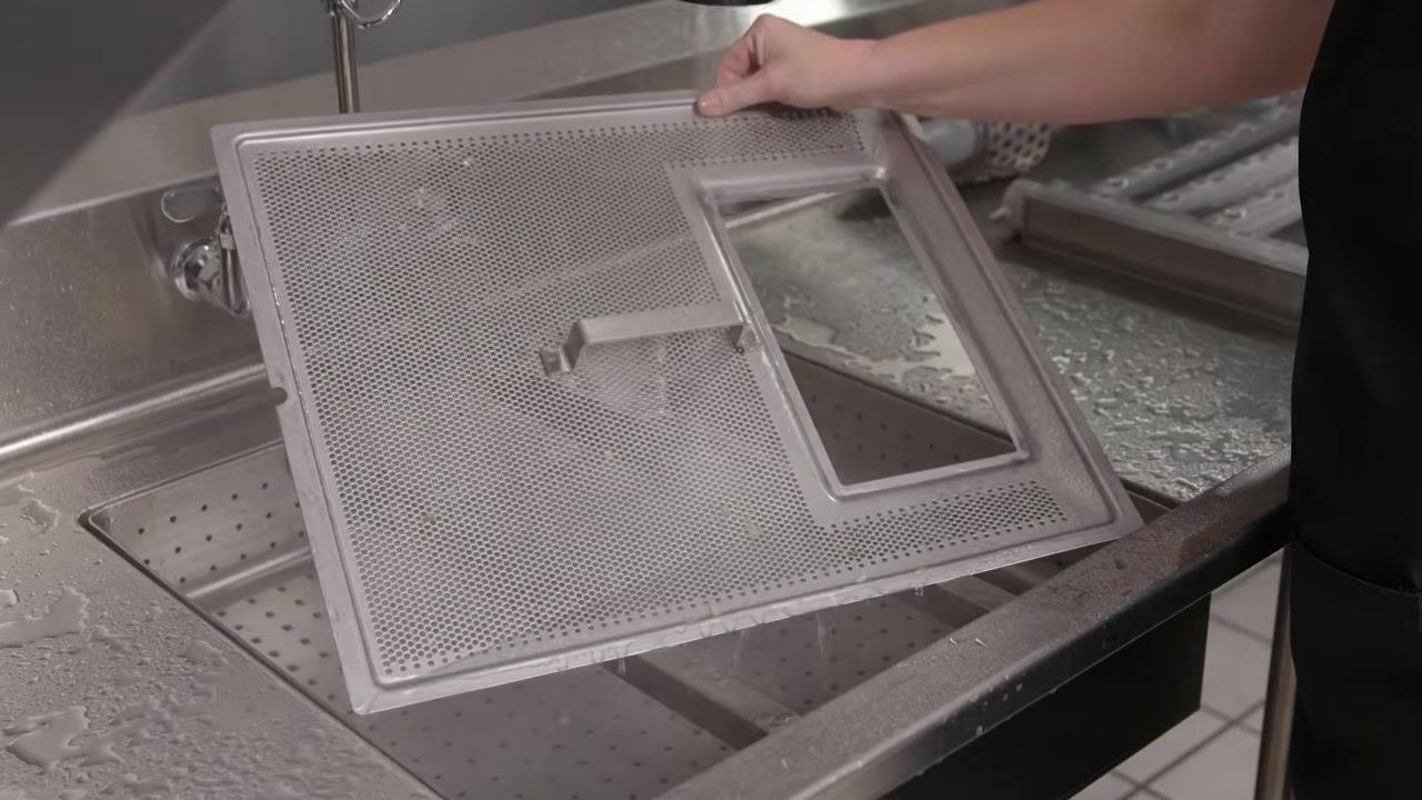 Strainer pan being rinsed under running water in a sink