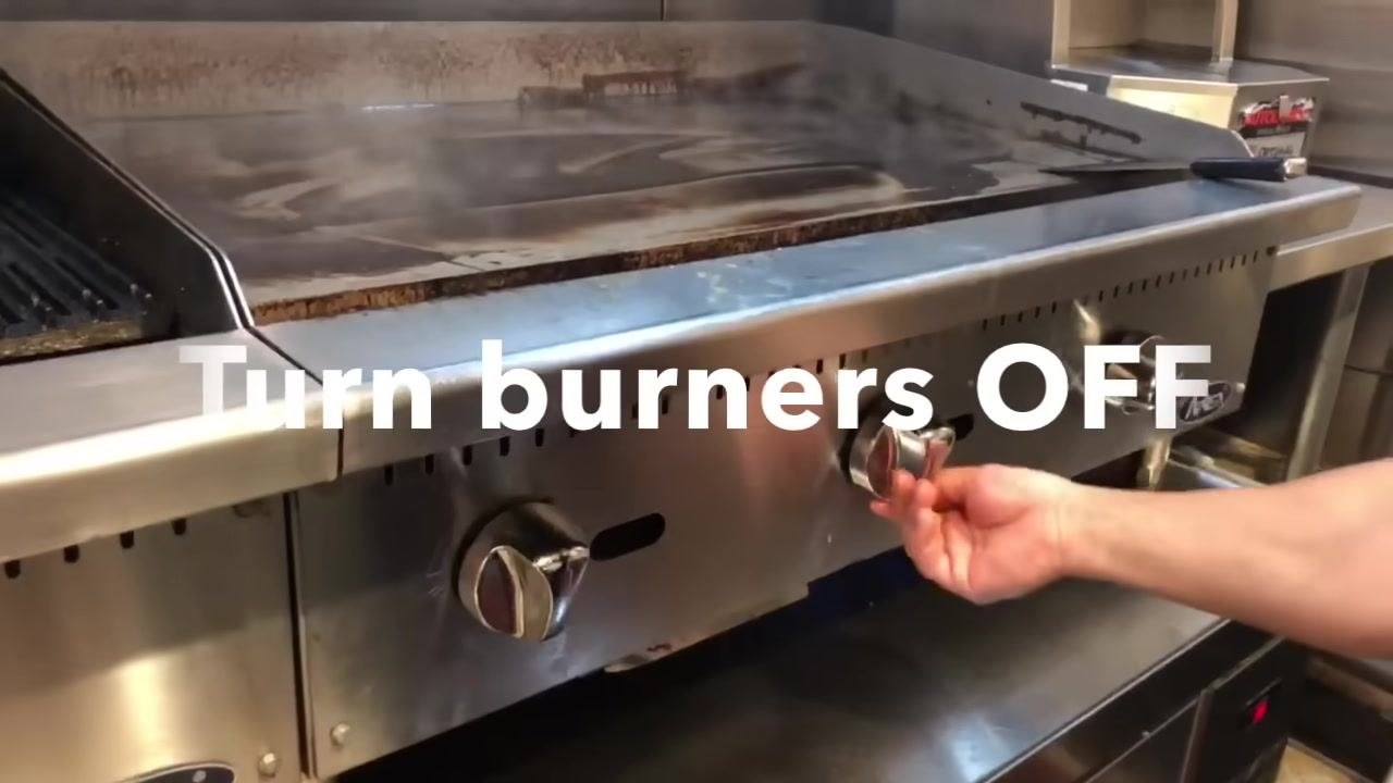 A hand turning the burner knob to the off position on a commercial flat-top grill. Large on-screen text reads "Turn burners OFF."