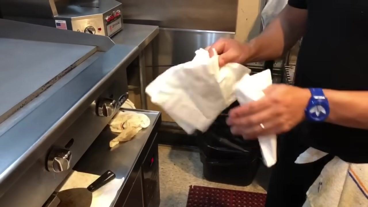 A person holding clean towels, preparing to dry the grill surface.