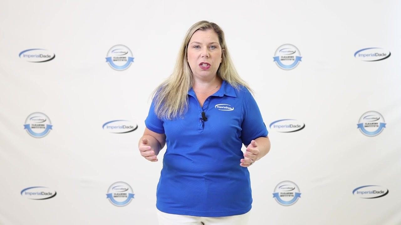 Presenter describing the cleaning solution, wearing blue ImperialDade shirt, standing in front of branded backdrop