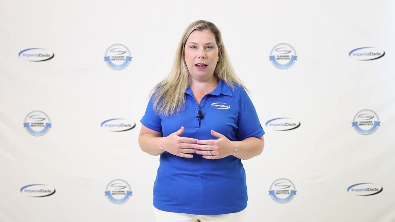 Presenter explaining the flushing process, wearing blue ImperialDade shirt, standing in front of branded backdrop