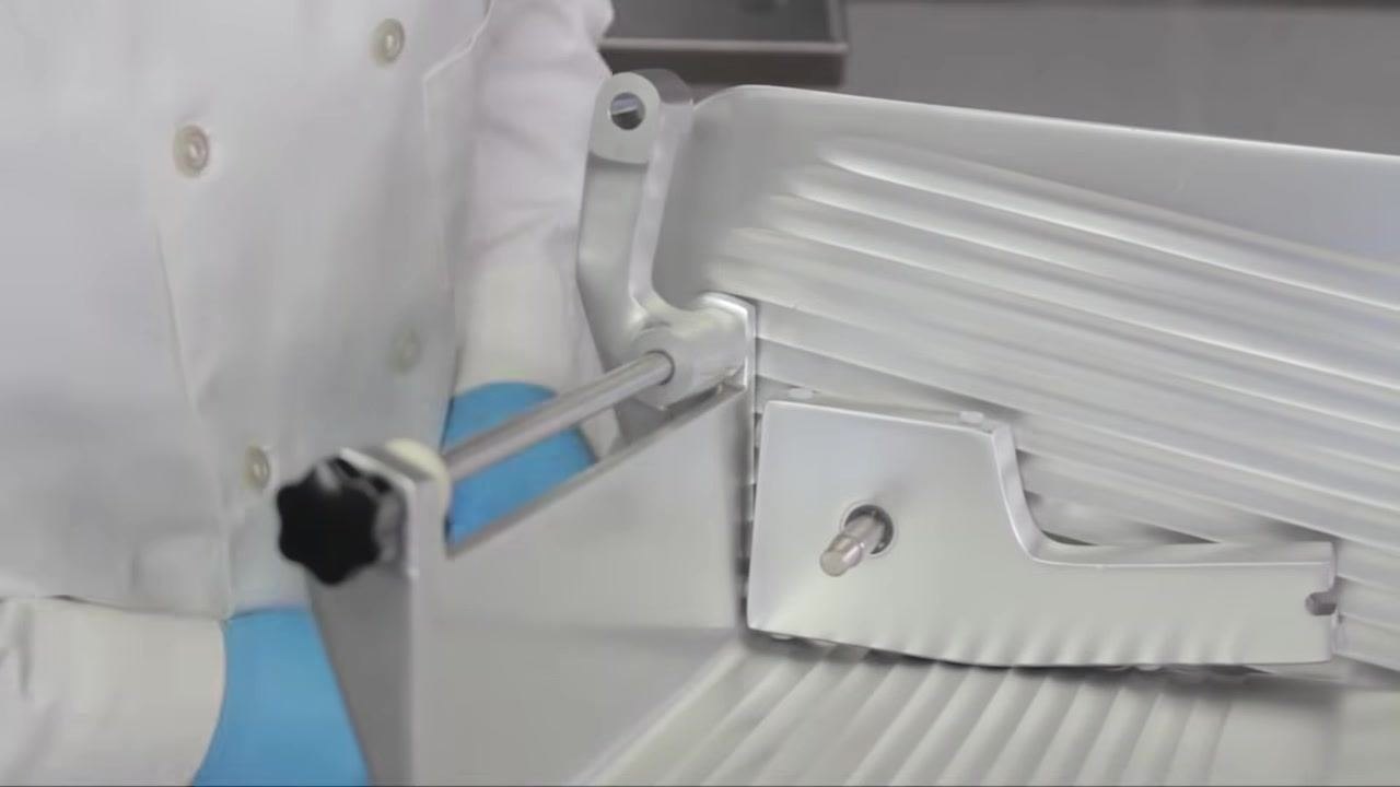 Operator placing a thin plastic spacing washer onto the feed grip rod inside the slicer carriage.