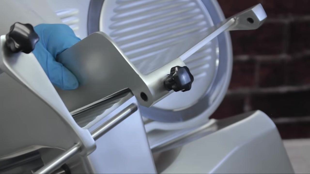Operator holding the assembled grip mechanism, showing the adjustment knobs and rods securely in place on the slicer.