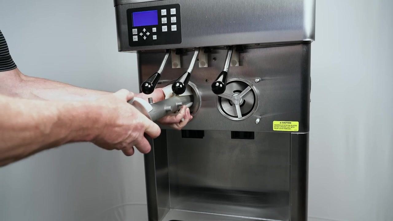 Hands assembling a metal spring into a white plastic flight. Several other flights and orange O-rings are organized in a black tray on the work surface.