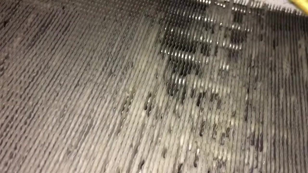 Evaporator coil fins with visible foam and residual grime, showing the need for thorough rinsing