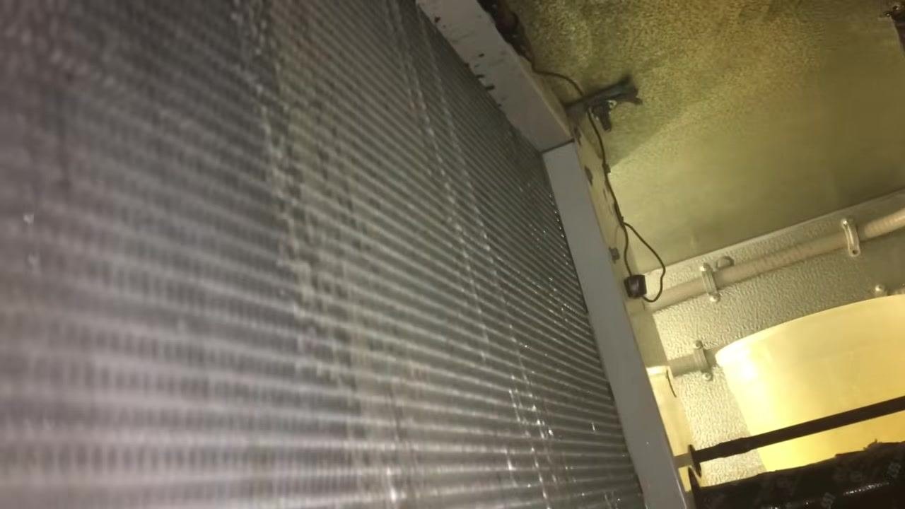 Close-up of the HVAC coil, sprayer wand tip, yellow bucket, and pipes in the mechanical room