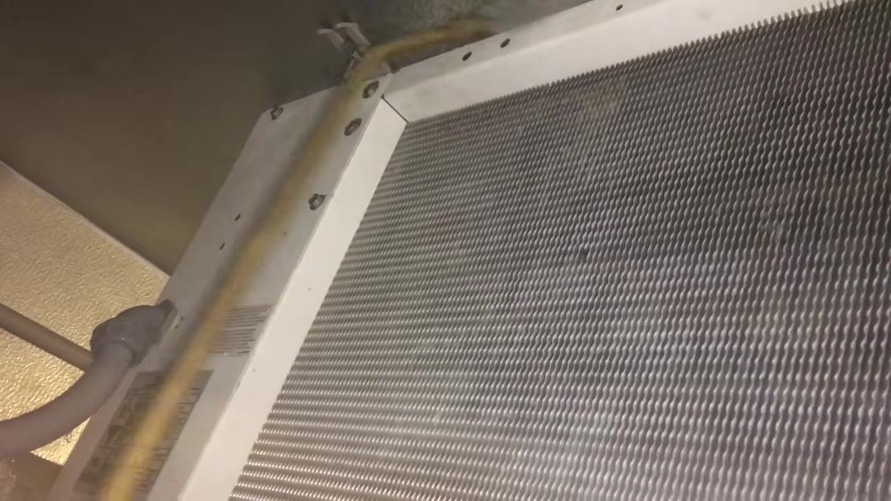 Close-up of HVAC coil, white metal frame, mounting screws, and copper pipe during thorough rinsing