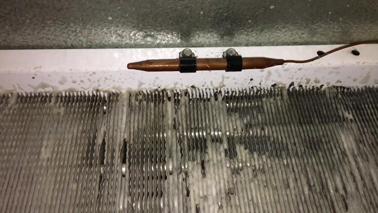 Hand holding a can of Nu-Brite Condenser Coil Cleaner next to other cleaning supplies