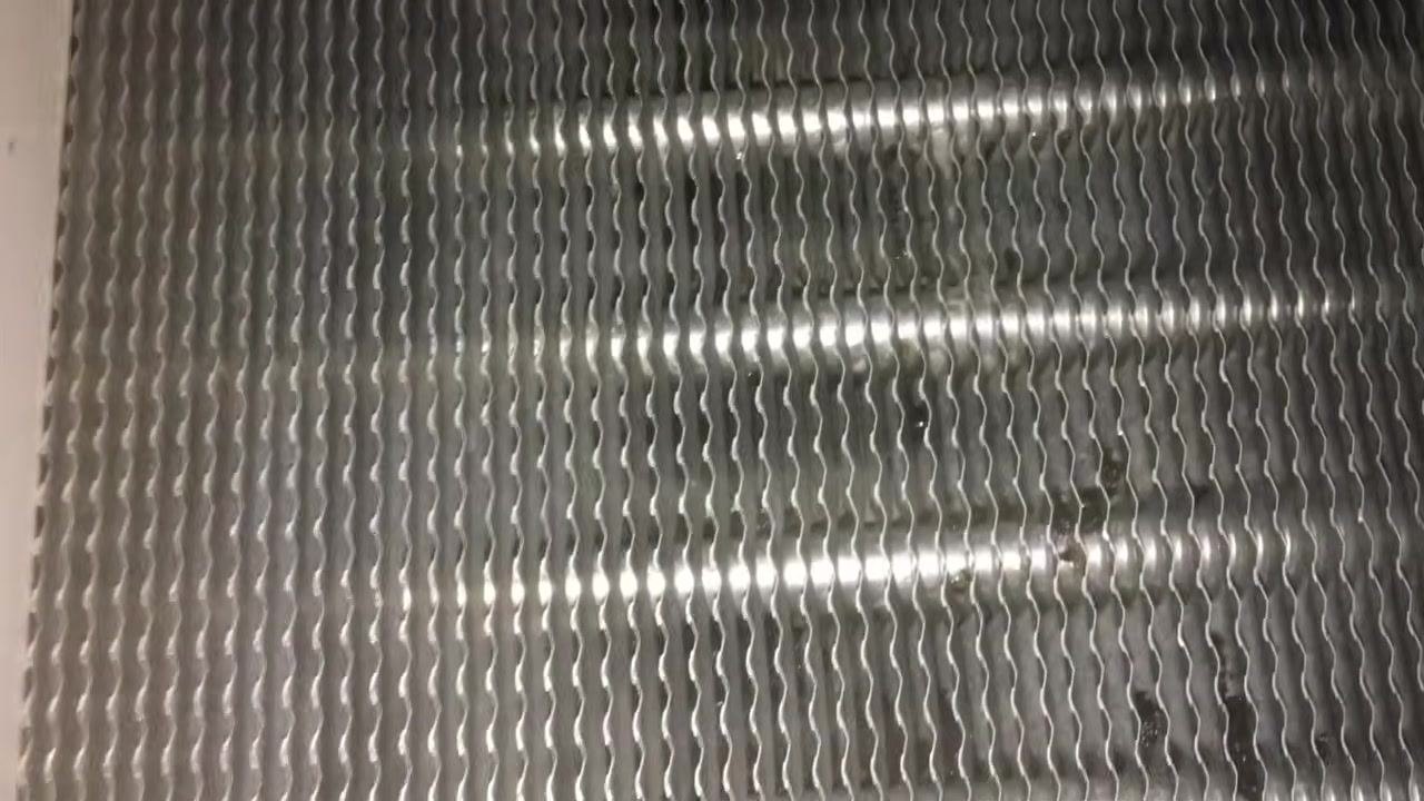 Close-up of the upper left corner of the evaporator coil showing clean metallic fins and a mounting screw