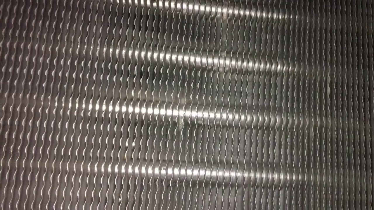 Close-up of evaporator coil fins showing a clean, metallic surface with bright reflections