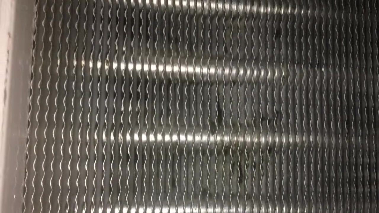 Hand holding a copper drain line connected to the evaporator pan, showing where a union could be installed