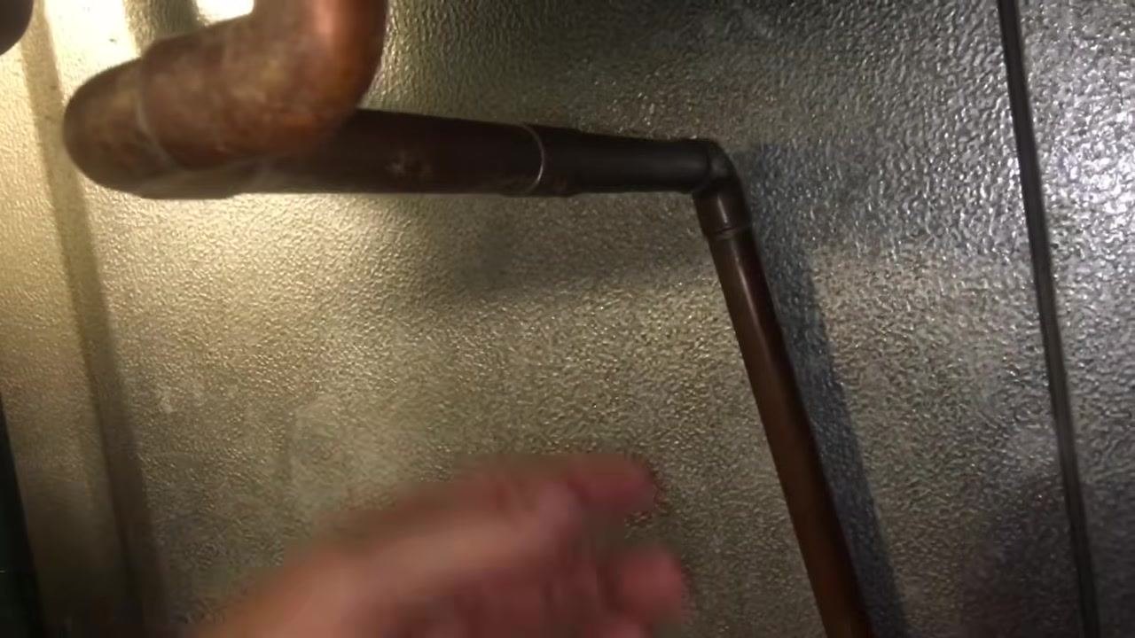 Wide view of the copper drain line running along the wall, with food storage containers below