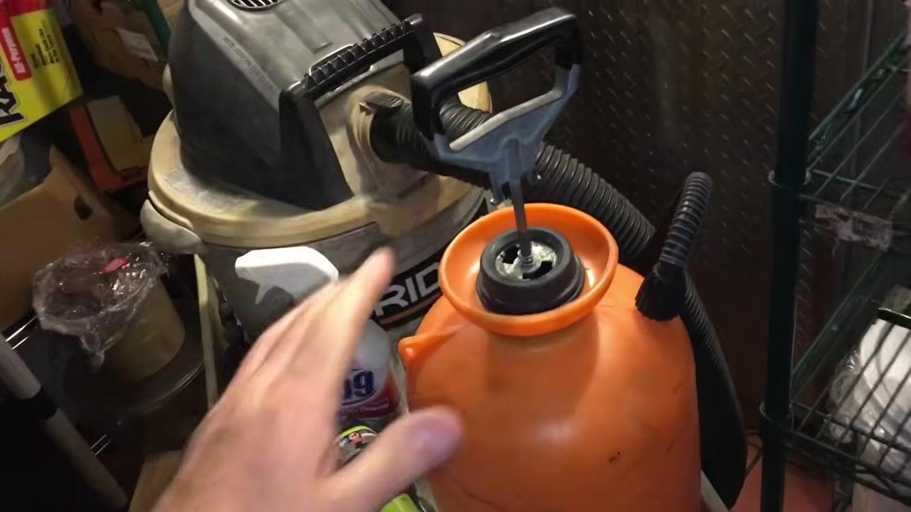 Hand holding a vacuum hose with a furry attachment near a stocked cleaning cart