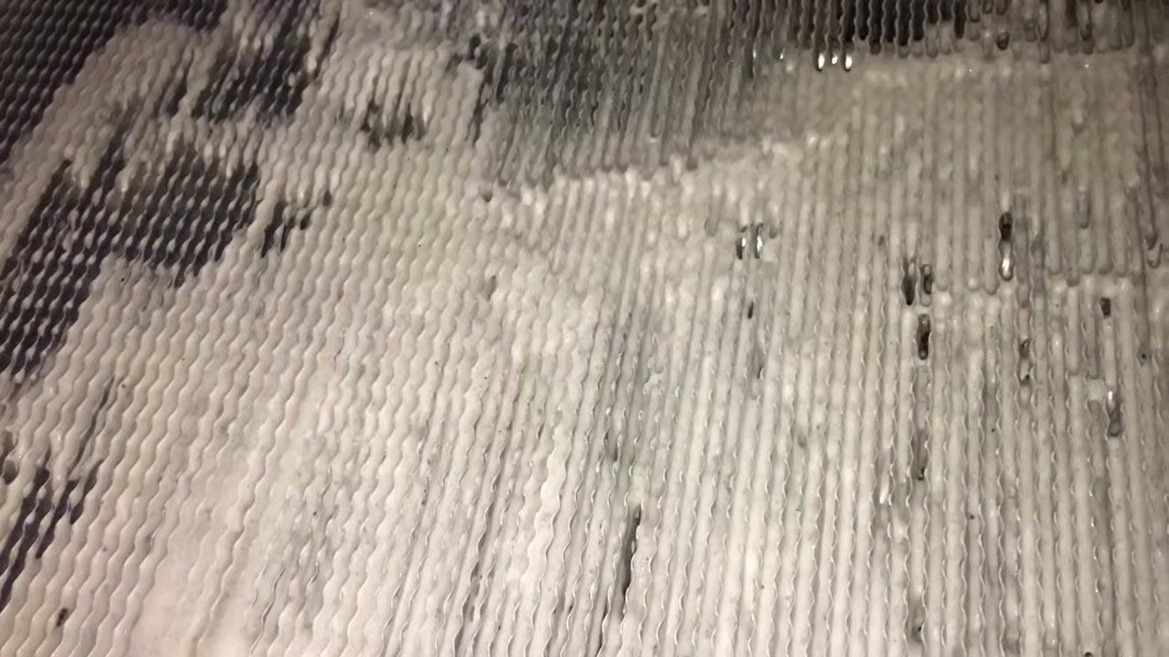 Hand brushing the foamed evaporator coil with a plastic brush