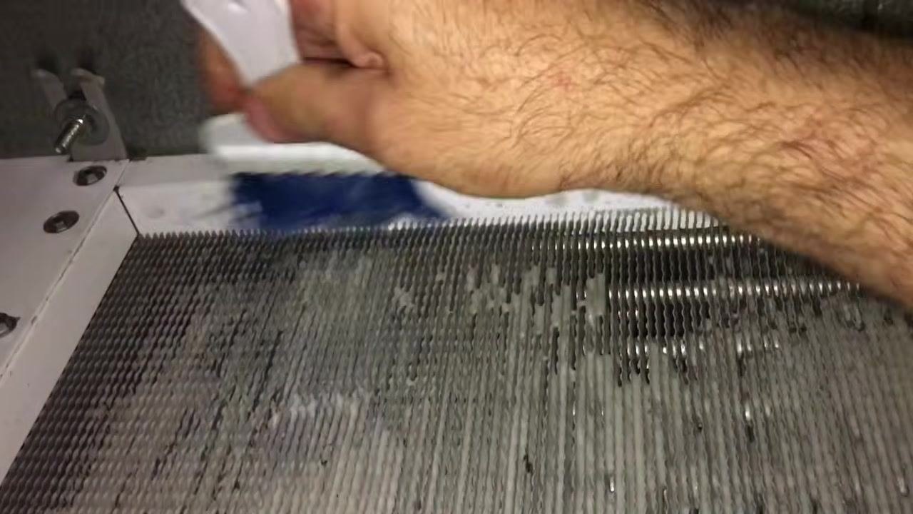 Close-up of evaporator coil fins with foaming cleaner showing texture and buildup being addressed