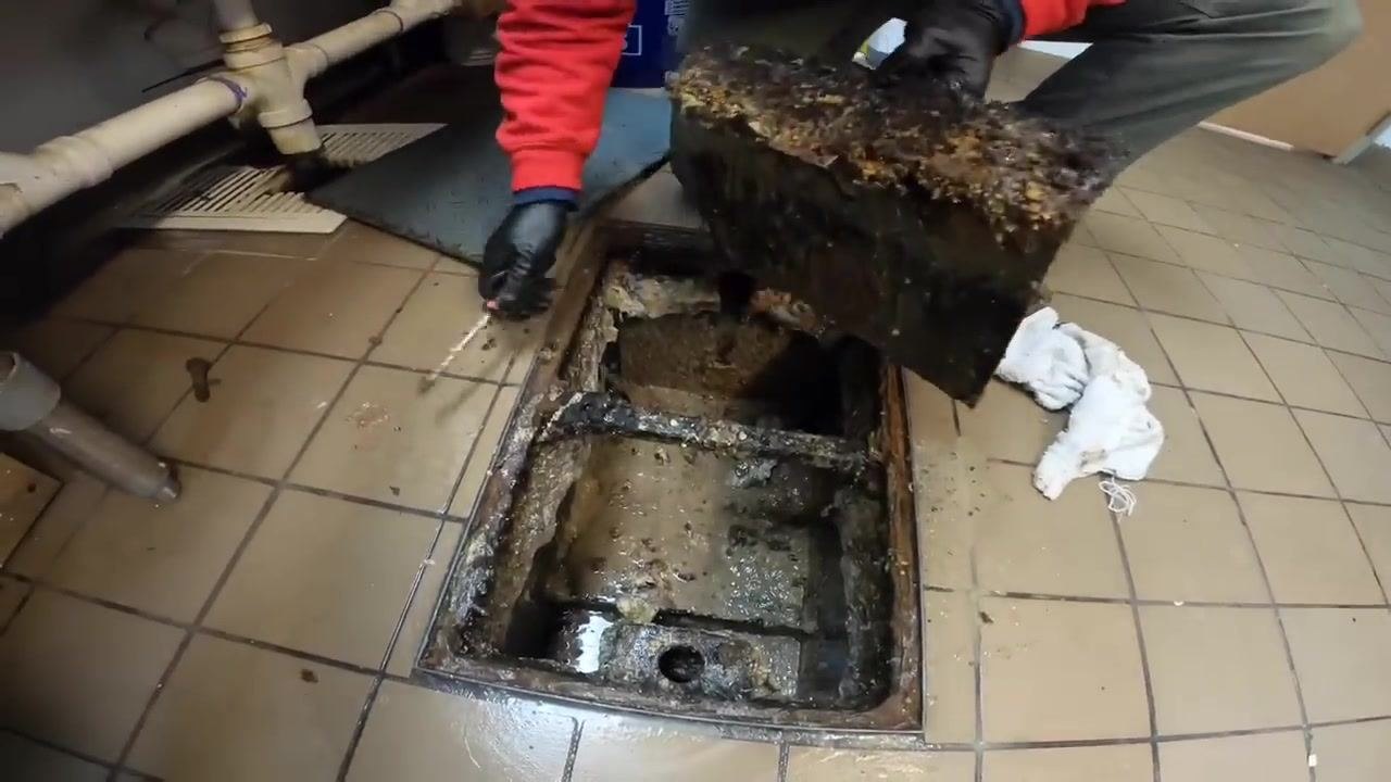 Technician turning on the faucet at a stainless steel sink, with a hose attached for flushing.