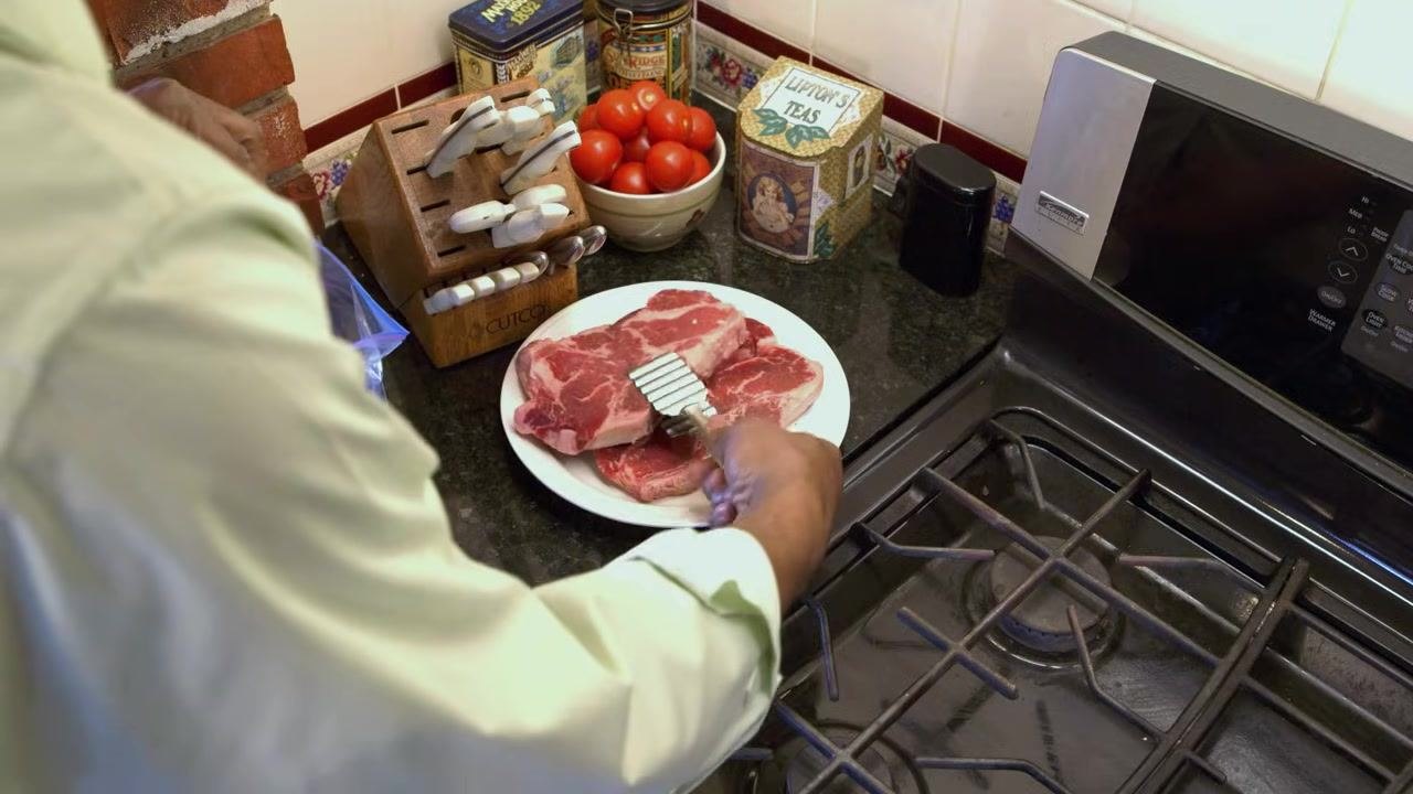 Clean, organized kitchen with utensils, a refrigerator, and a stove, set up for food preparation